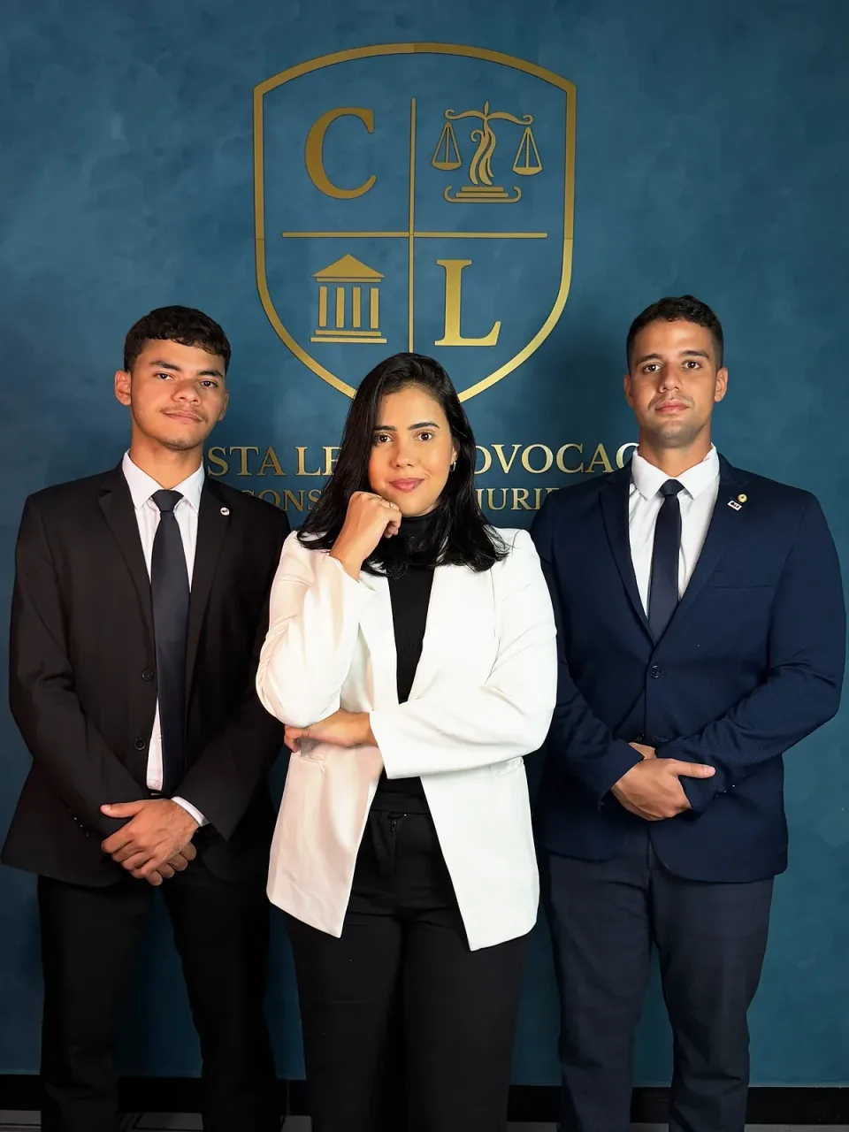 Eduardo Oliveira, Bel.ª Karen Costa Leite e Dr. Bruno Costa Leite, lado a lado, diante da parede azul com o brasão dourado e o nome do escritório.