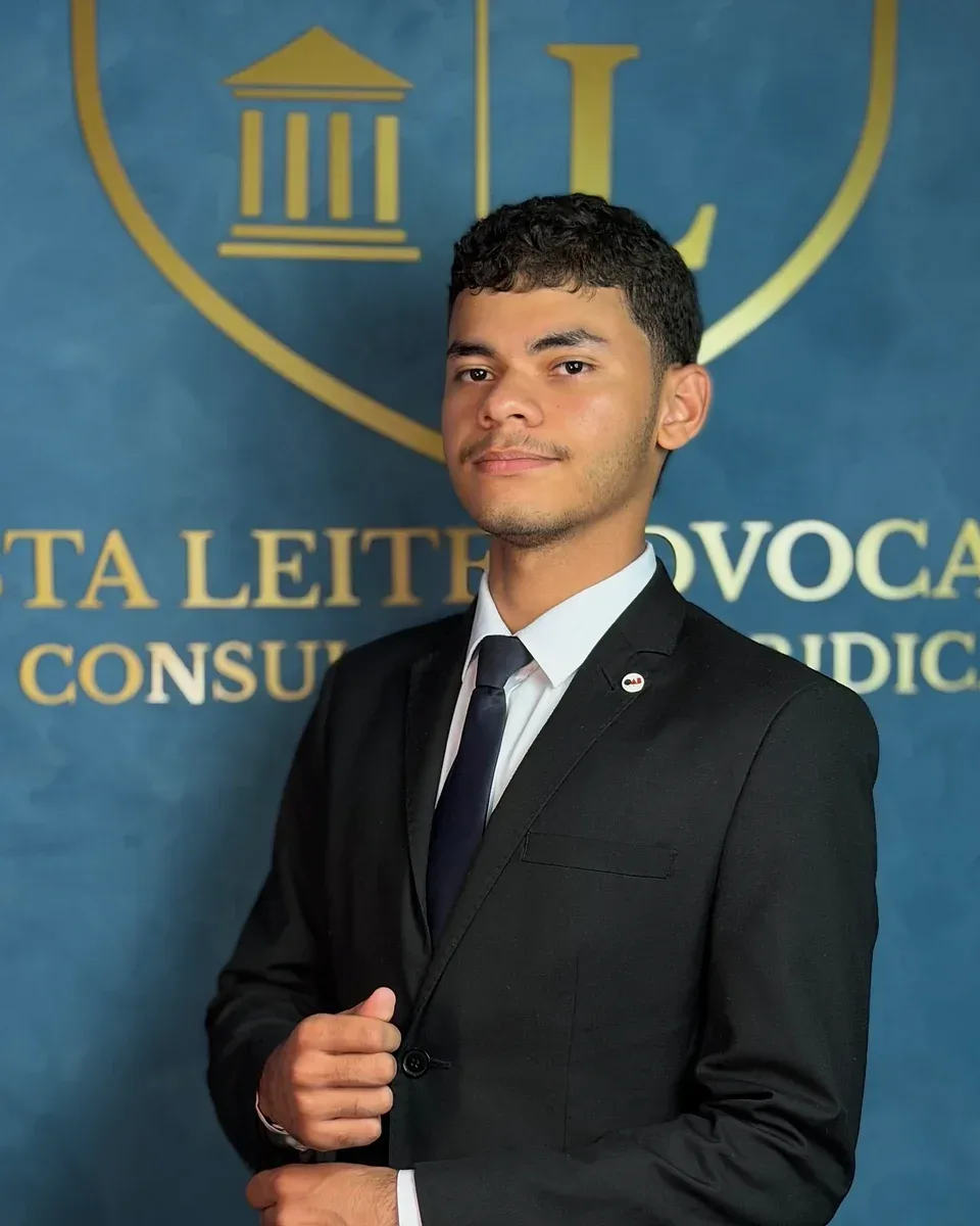 Eduardo Oliveira, de terno preto e gravata azul, diante da parede azul com o brasão dourado do escritório.